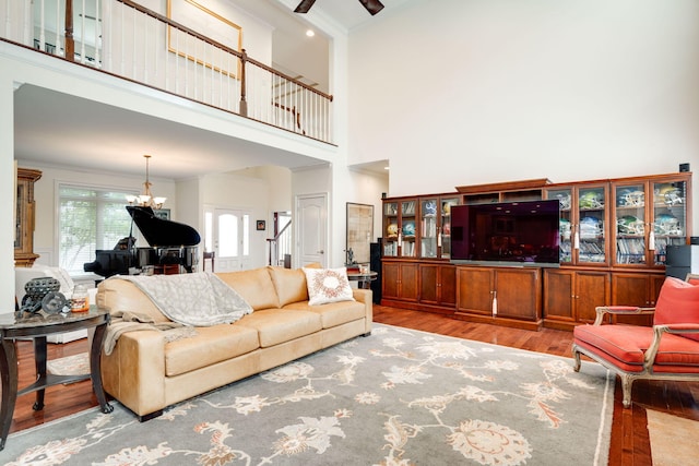 living room featuring light hardwood / wood-style flooring, a high ceiling, a notable chandelier, and ornamental molding