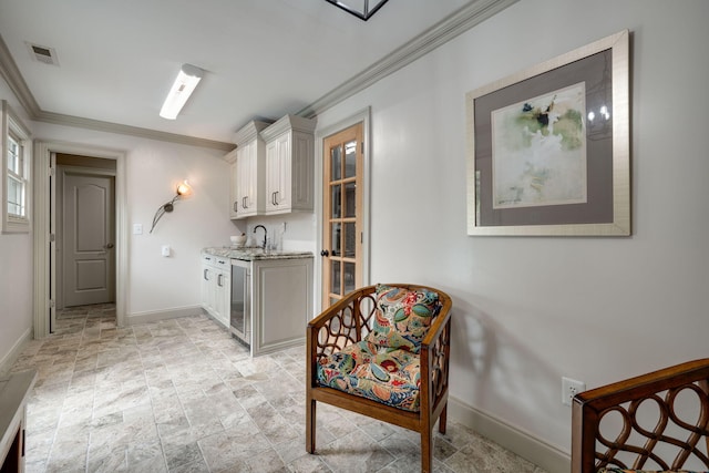 living area with beverage cooler, crown molding, and sink