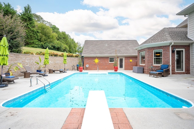 view of swimming pool featuring a diving board and a patio area