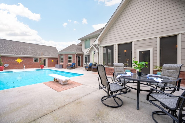 view of swimming pool featuring a diving board and a patio area