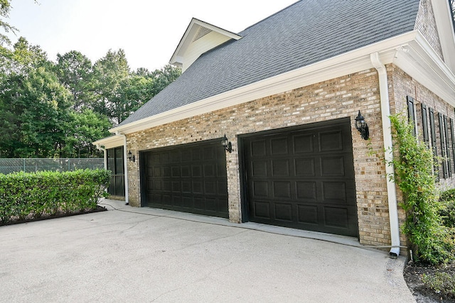 garage featuring driveway and fence