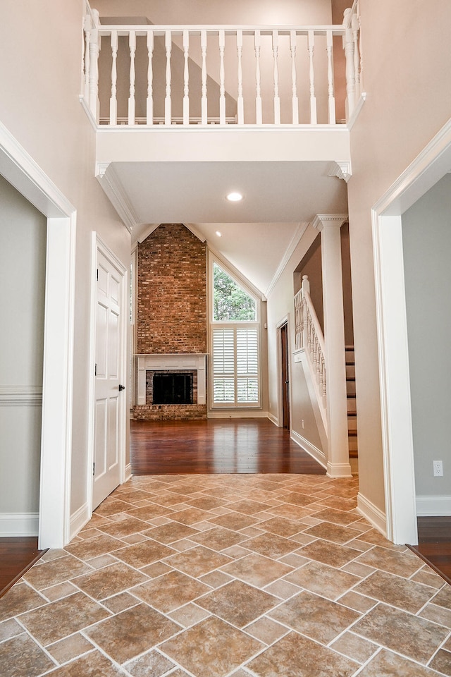 unfurnished living room featuring high vaulted ceiling, wood-type flooring, a fireplace, and crown molding