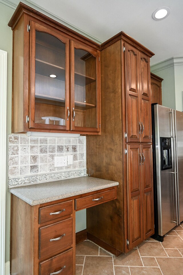 kitchen featuring built in desk, decorative backsplash, and stainless steel fridge with ice dispenser