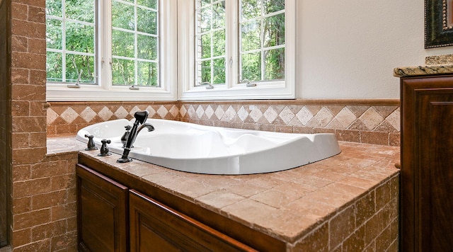 bathroom featuring vanity and tiled tub