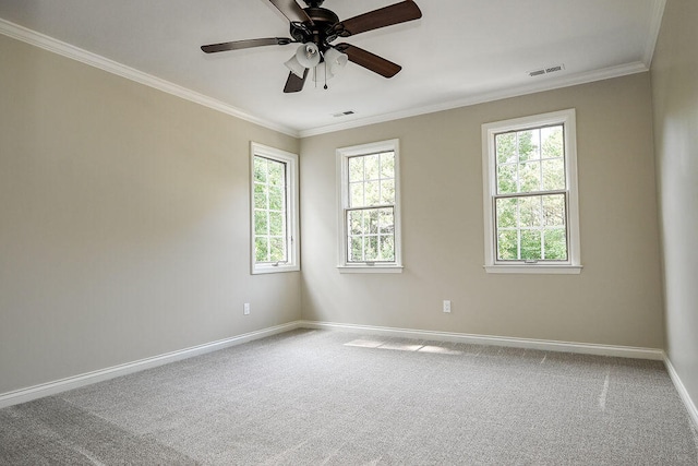 carpeted spare room featuring baseboards, visible vents, ceiling fan, and crown molding