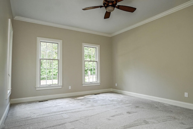 spare room featuring light colored carpet, visible vents, ornamental molding, a ceiling fan, and baseboards