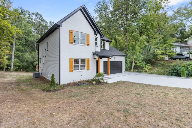 view of front of house featuring central AC, a front yard, and a garage