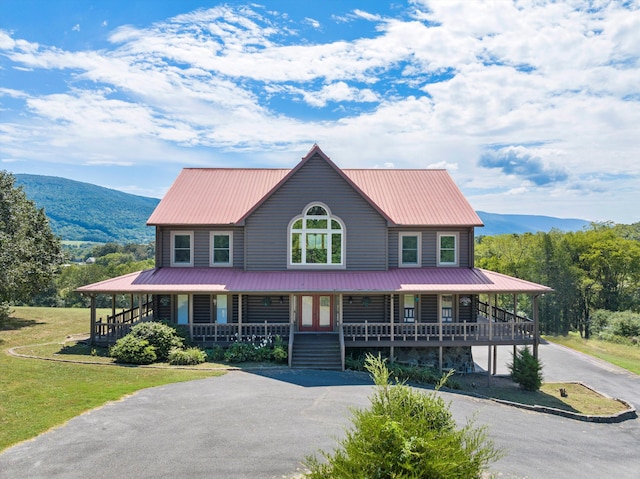 farmhouse inspired home with a porch, a mountain view, and a front yard