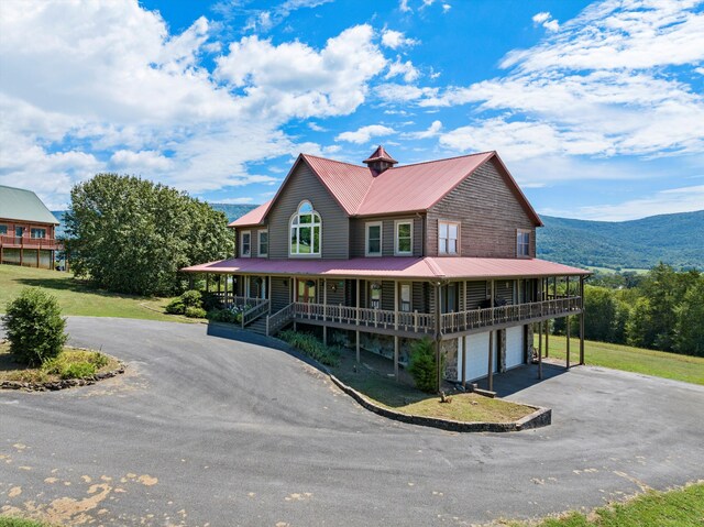 farmhouse with a mountain view, a garage, and a porch