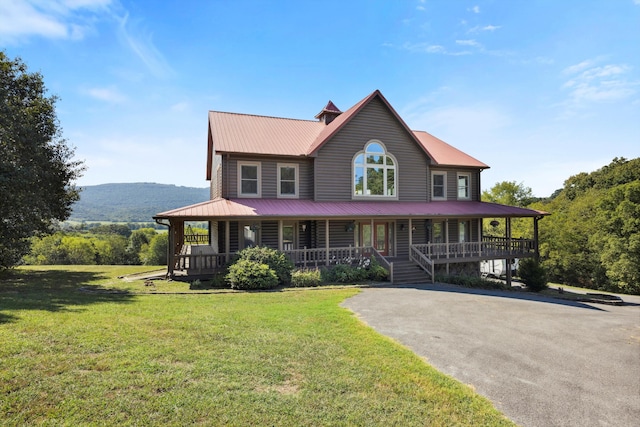 country-style home featuring a porch, a front lawn, and metal roof