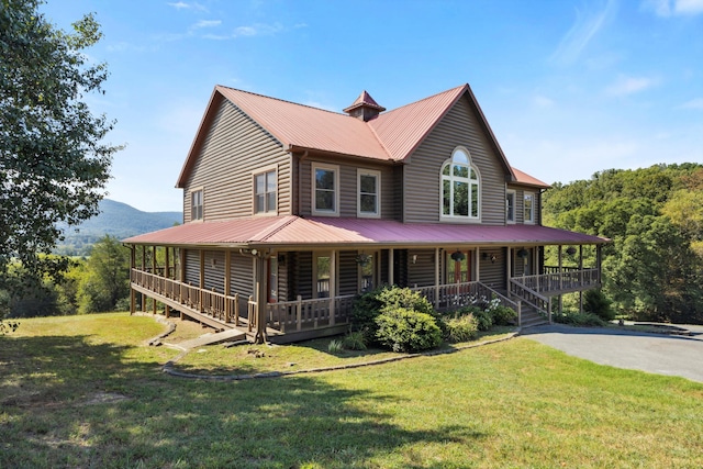 country-style home with covered porch, driveway, metal roof, and a front lawn