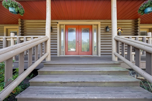 doorway to property featuring log siding, french doors, and a porch