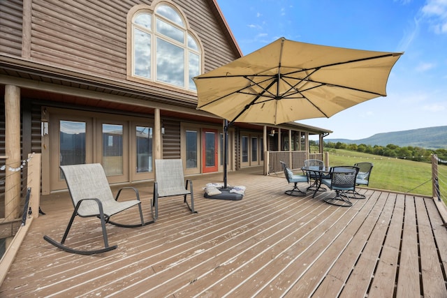 deck with outdoor dining area, french doors, and a mountain view