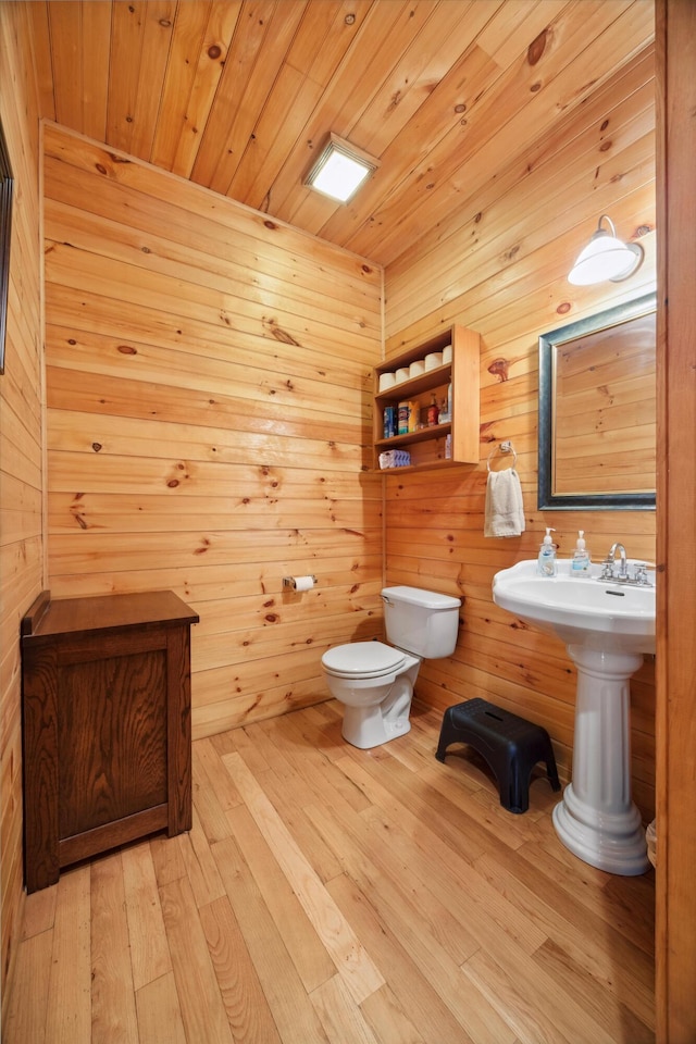 bathroom with hardwood / wood-style floors, wooden ceiling, wooden walls, and toilet