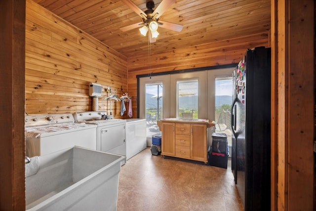 laundry room with wooden walls, wooden ceiling, ceiling fan, laundry area, and washing machine and clothes dryer