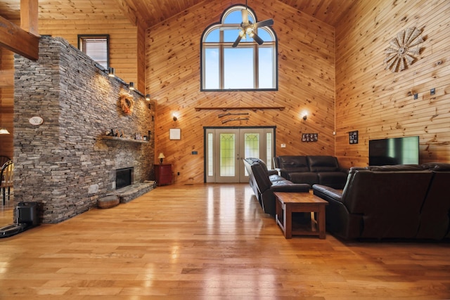 unfurnished living room with french doors, a stone fireplace, ceiling fan, and hardwood / wood-style flooring