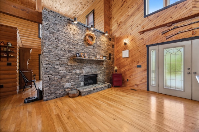 unfurnished living room featuring a fireplace, wooden ceiling, a towering ceiling, hardwood / wood-style flooring, and log walls