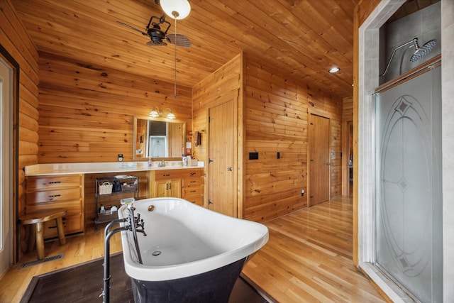 full bath with wooden walls, wood finished floors, visible vents, a freestanding bath, and wooden ceiling