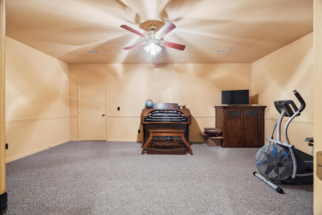 workout room featuring ceiling fan, carpet flooring, and a textured ceiling