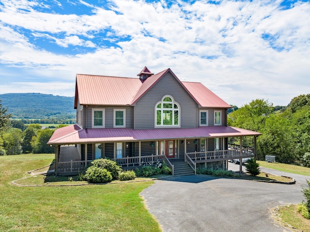 farmhouse inspired home with covered porch, driveway, metal roof, and a front lawn