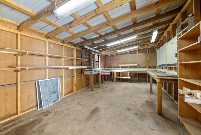 miscellaneous room with concrete flooring, a workshop area, and vaulted ceiling