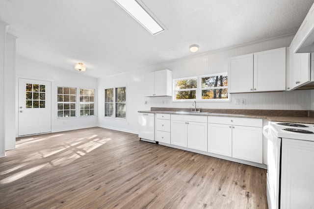 kitchen with white appliances, sink, light wood-type flooring, white cabinetry, and vaulted ceiling