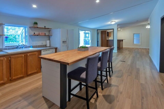 kitchen with vaulted ceiling, light hardwood / wood-style floors, sink, white fridge with ice dispenser, and butcher block counters