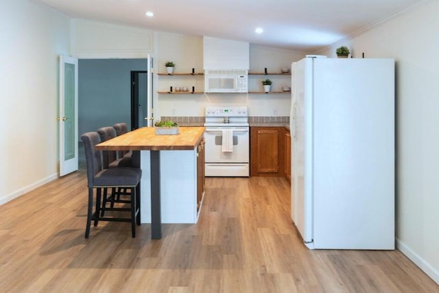 kitchen with lofted ceiling, white appliances, a center island, and wood counters