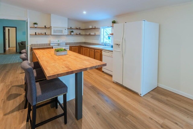 kitchen with white appliances, light hardwood / wood-style flooring, butcher block counters, and a breakfast bar area