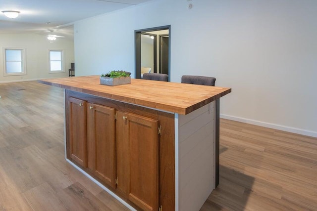 kitchen featuring a center island, light hardwood / wood-style flooring, butcher block countertops, and ceiling fan