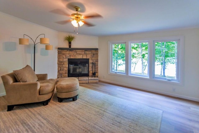 living room featuring light wood-type flooring, ceiling fan, and a fireplace