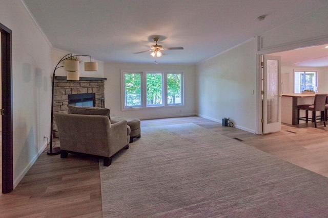 living room with a fireplace, crown molding, hardwood / wood-style floors, lofted ceiling, and ceiling fan