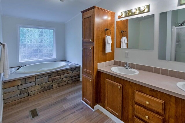 bathroom featuring wood-type flooring, shower with separate bathtub, crown molding, and vanity