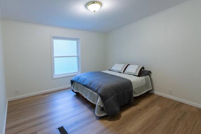 bedroom with ornamental molding and hardwood / wood-style floors