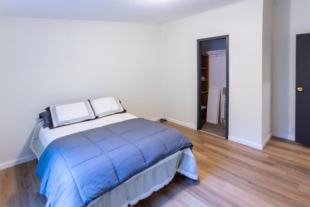 bedroom with a closet, wood-type flooring, and crown molding