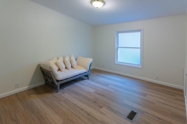 sitting room with ornamental molding and light hardwood / wood-style floors