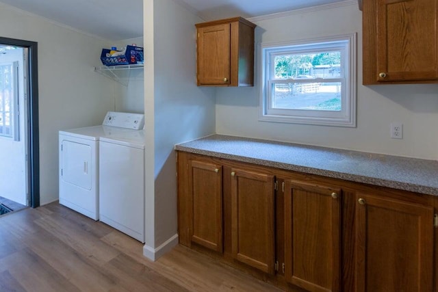 clothes washing area featuring cabinets, light hardwood / wood-style floors, crown molding, and washer and dryer