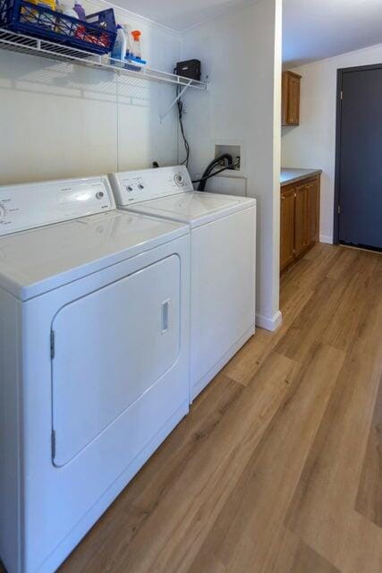 laundry area with light hardwood / wood-style floors and washing machine and clothes dryer