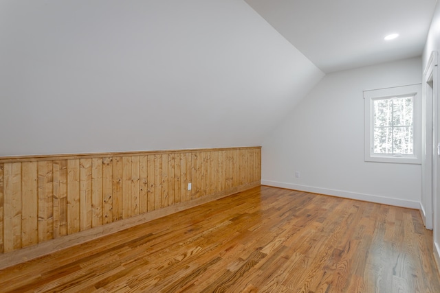 additional living space featuring vaulted ceiling and light wood-type flooring