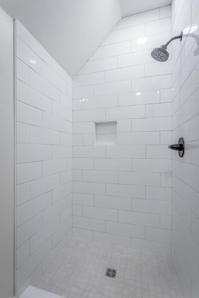 bathroom featuring lofted ceiling and tiled shower