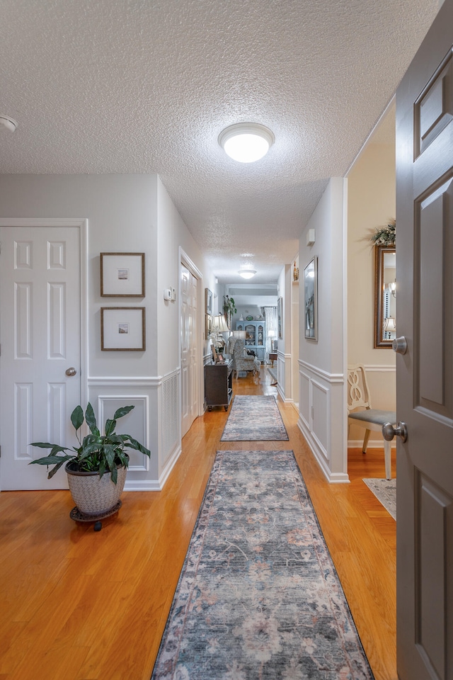 hallway featuring light hardwood / wood-style floors and a textured ceiling