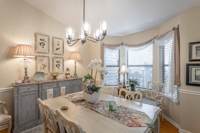 dining area featuring hardwood / wood-style floors, vaulted ceiling, a notable chandelier, and a textured ceiling