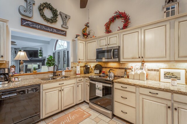 kitchen with cream cabinets, stainless steel appliances, backsplash, sink, and light tile patterned floors