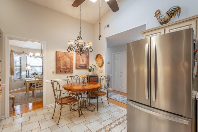 dining room featuring light hardwood / wood-style flooring, ceiling fan with notable chandelier, and high vaulted ceiling