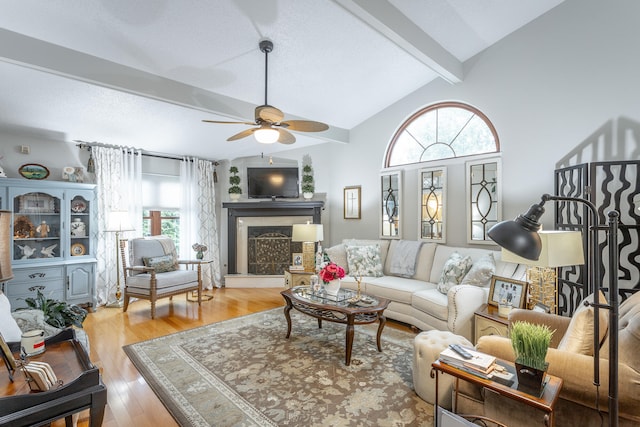 living room with vaulted ceiling with beams, light hardwood / wood-style floors, and ceiling fan