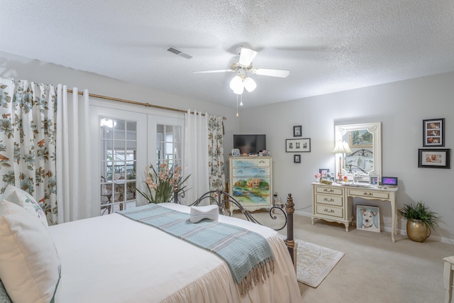 carpeted bedroom featuring french doors, a textured ceiling, and ceiling fan