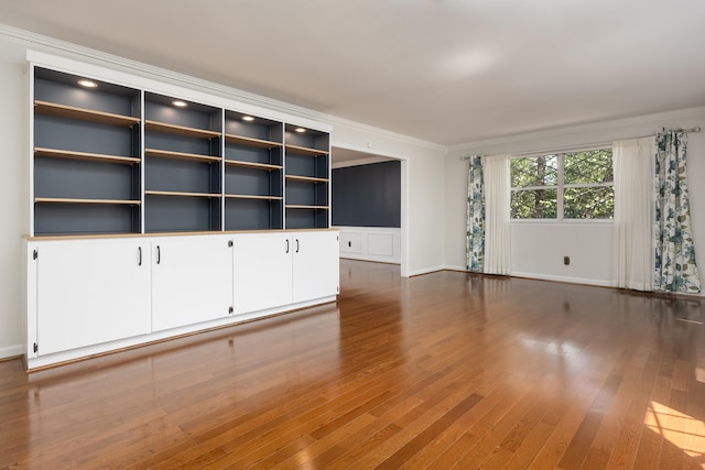 unfurnished living room with ornamental molding and hardwood / wood-style floors