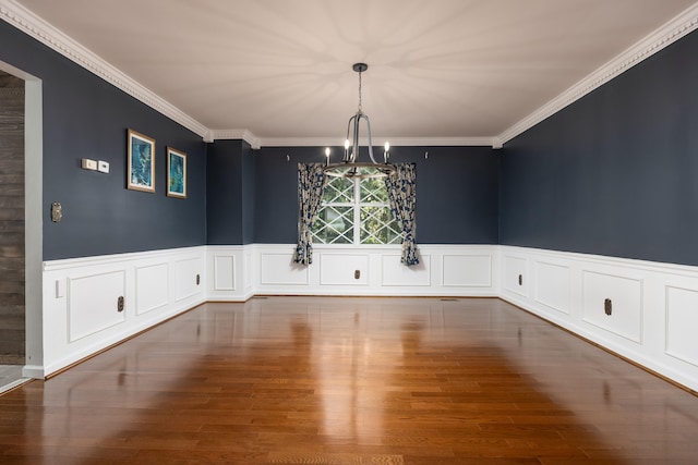 unfurnished dining area featuring wood-type flooring, ornamental molding, and an inviting chandelier