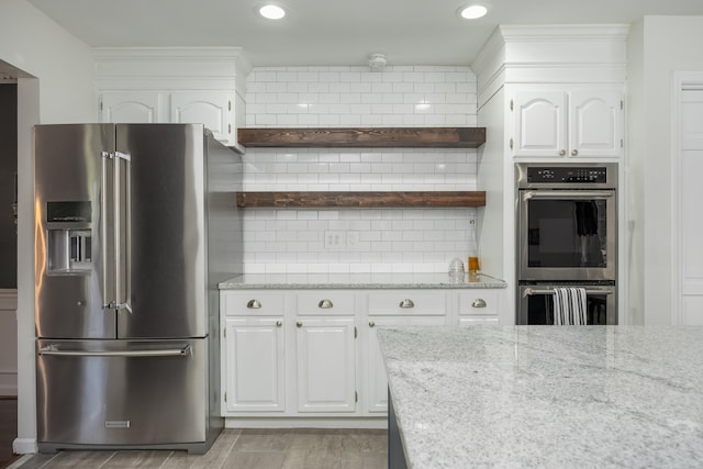 kitchen with stainless steel appliances, backsplash, light hardwood / wood-style floors, and white cabinetry