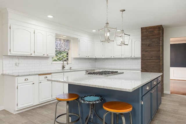 kitchen with stainless steel gas stovetop, backsplash, a center island, and white cabinets